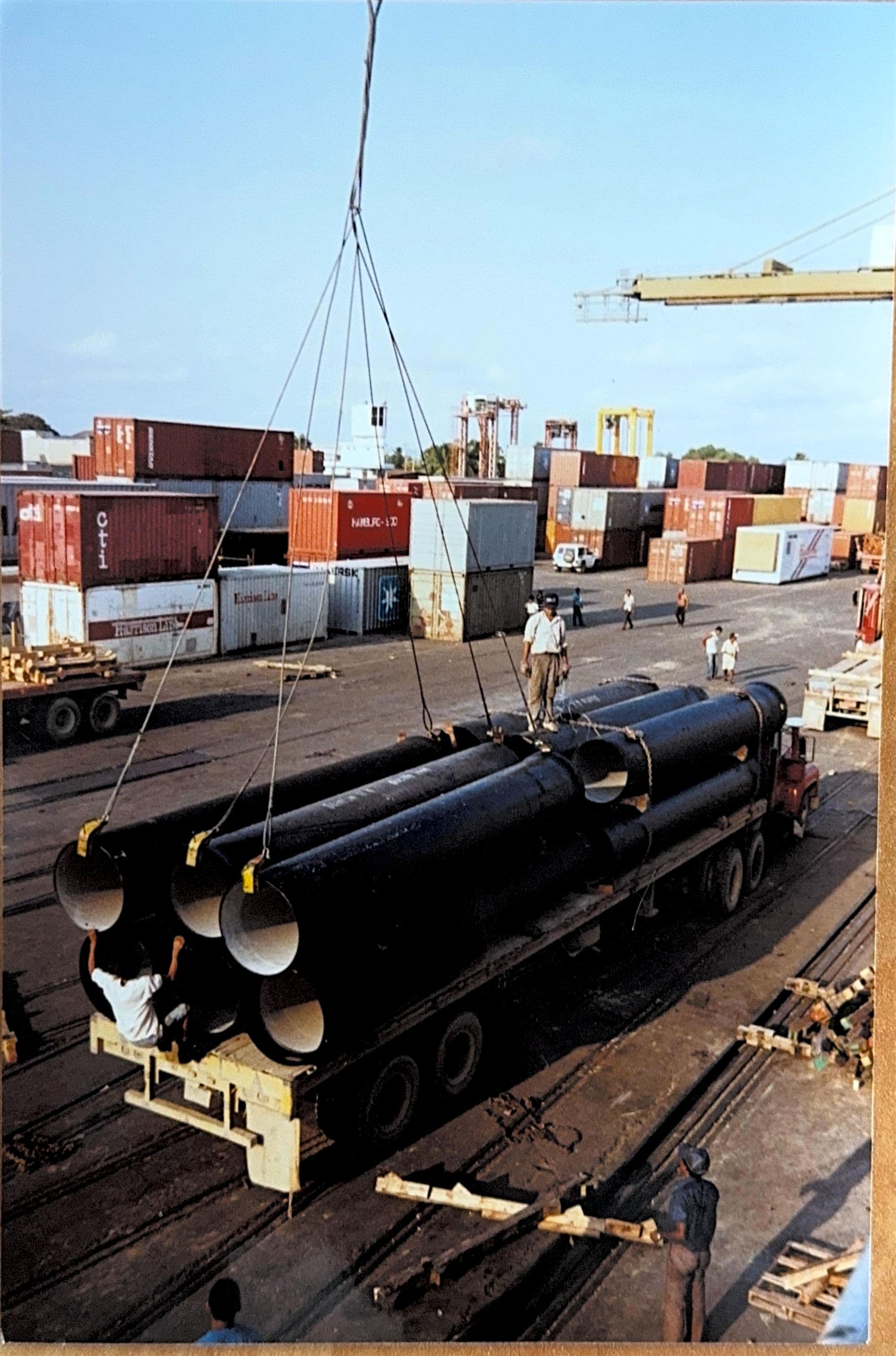 Crane lifting large-diameter pipe during port operations